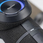 Macro detail of the SHARP GX-BT290-BK speaker, focusing on its top surface, woven grille, controls, and RGB ring.
