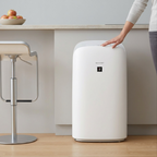 A professional scale reference photograph of the Sharp KCP70CW air purifier, placed beside a standard kitchen counter for visual context on size. The white appliance maintains the exact design details from the main product image.